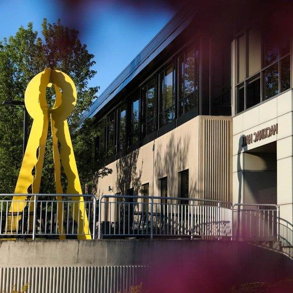 A building with the words Mackinac Hall has a yellow sculpture in front of it.